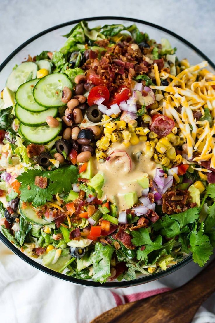 a salad in a glass bowl with dressing on top