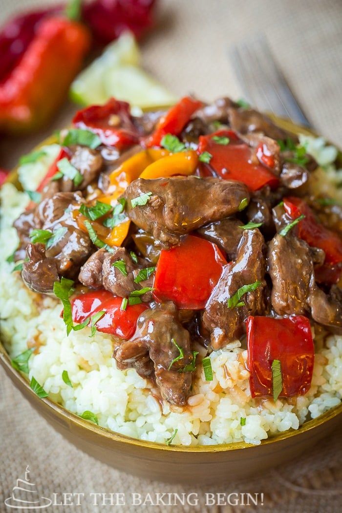 a close up of a plate of food with rice and meat on it, next to peppers