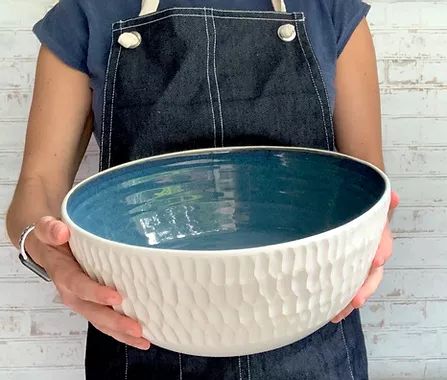 a person wearing an apron holding a large bowl in their hands with the handles down