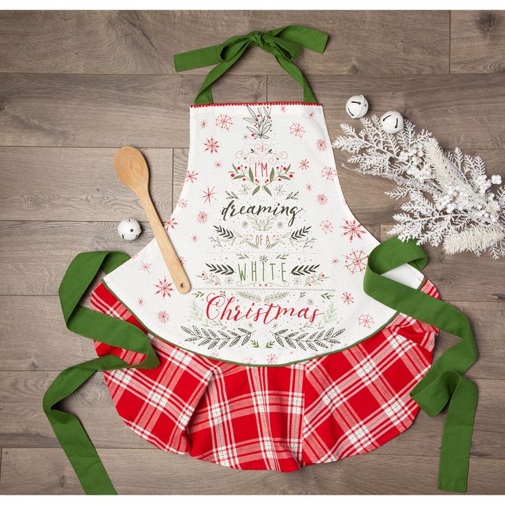 an apron with the words merry and christmas on it, next to some green ribbon