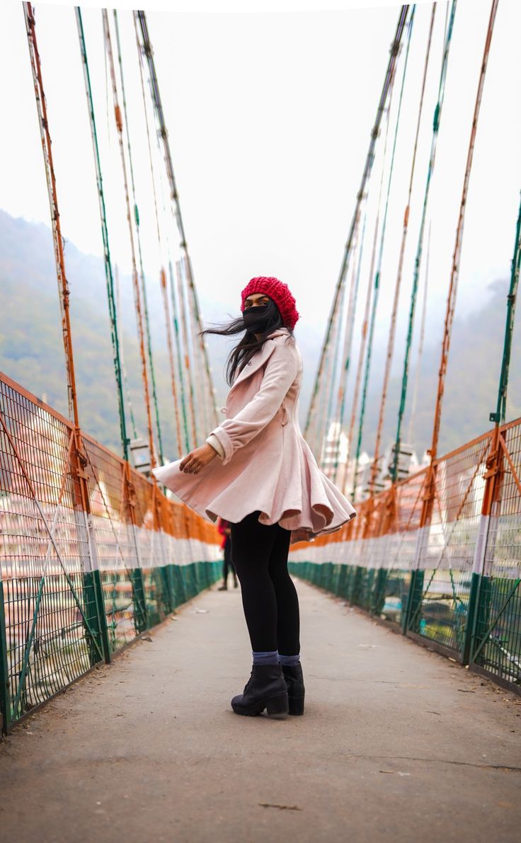 a woman standing on a bridge with her hair blowing in the wind and wearing black boots