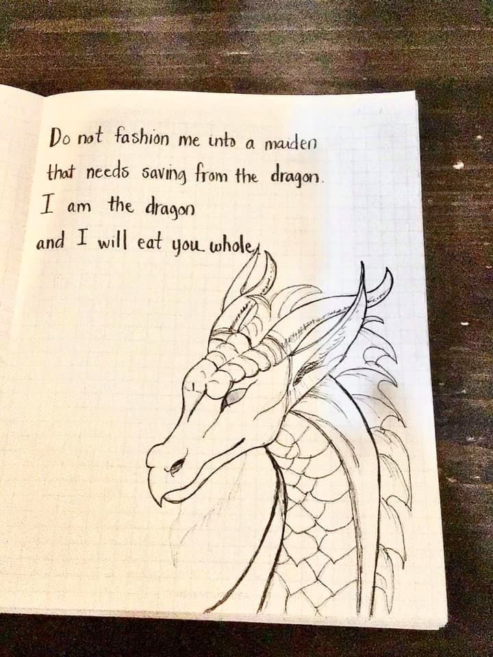 an open notebook with a drawing of a dragon on the page and handwritten quote