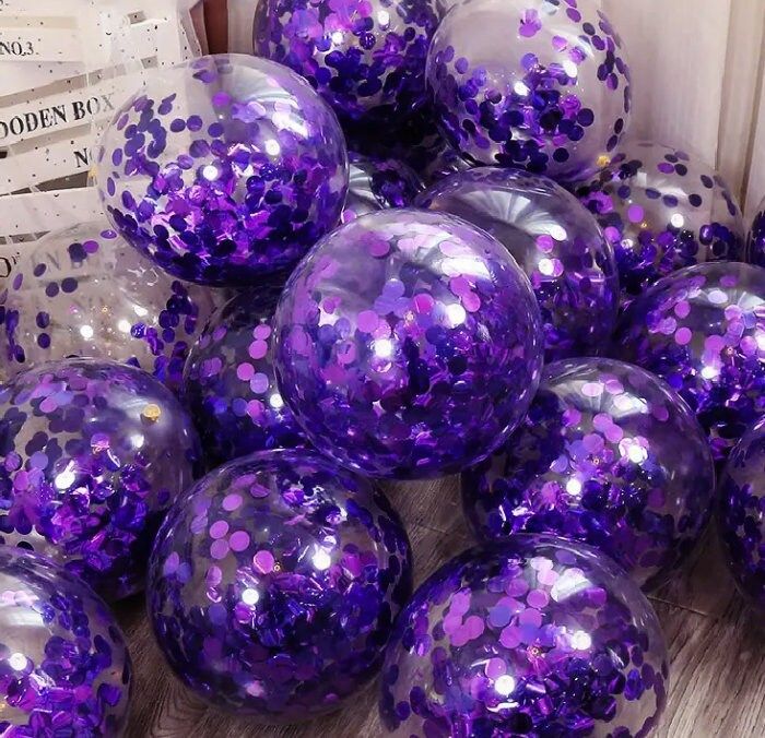 purple sequins are piled on top of each other in front of a box