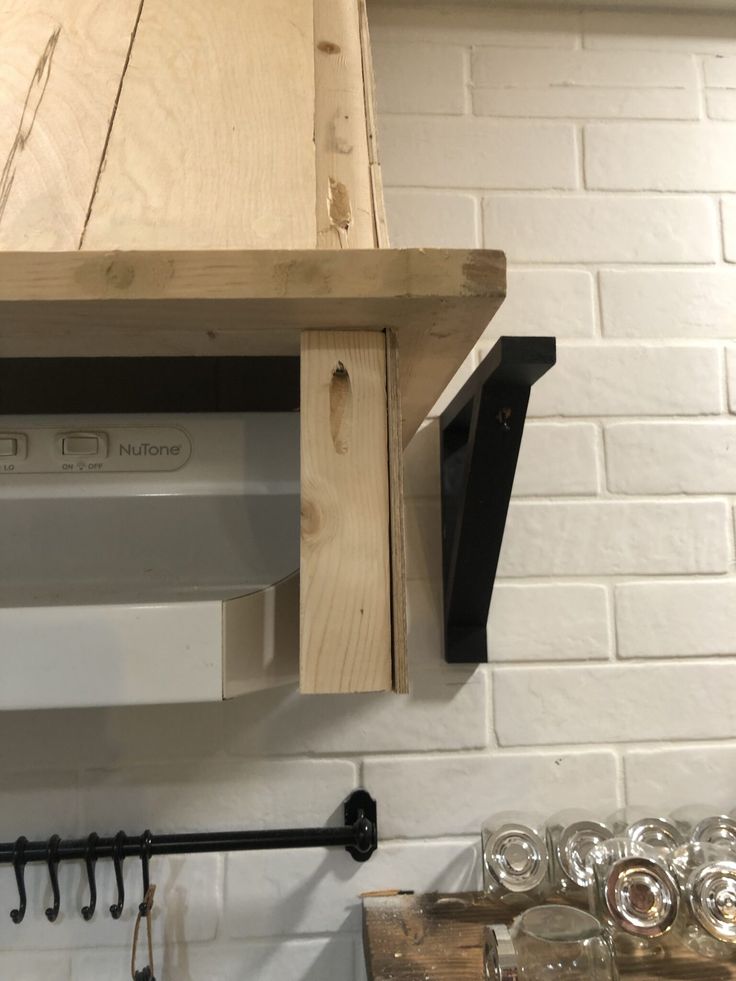 a kitchen with white brick walls and wooden cabinets, hanging utensils on the wall