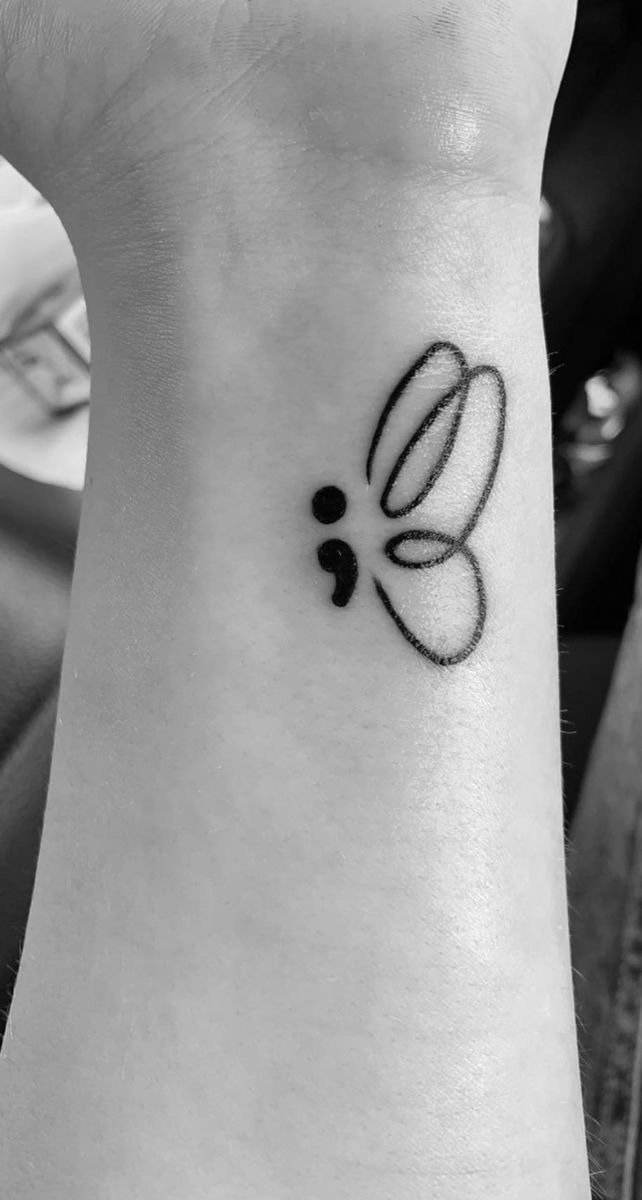 a small black and white flower tattoo on the wrist