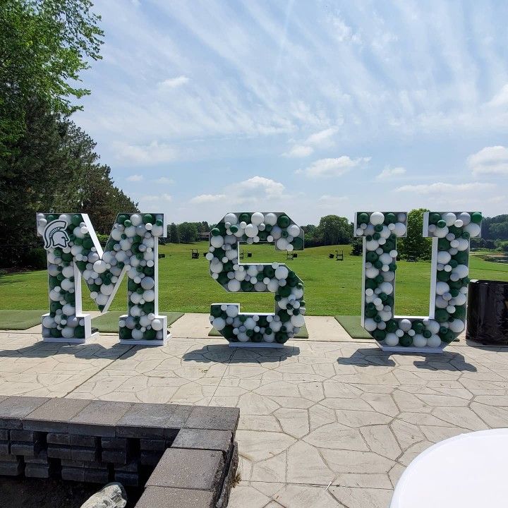 the letters are made out of plastic bottles and paper machs in front of a grassy field