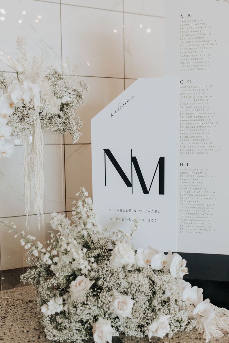 a bouquet of white flowers sitting on top of a counter next to a sign that says n m