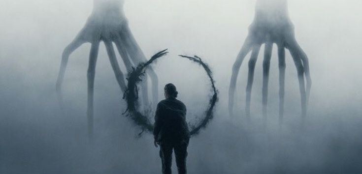 a man standing in front of two giant squid like creatures on a foggy day