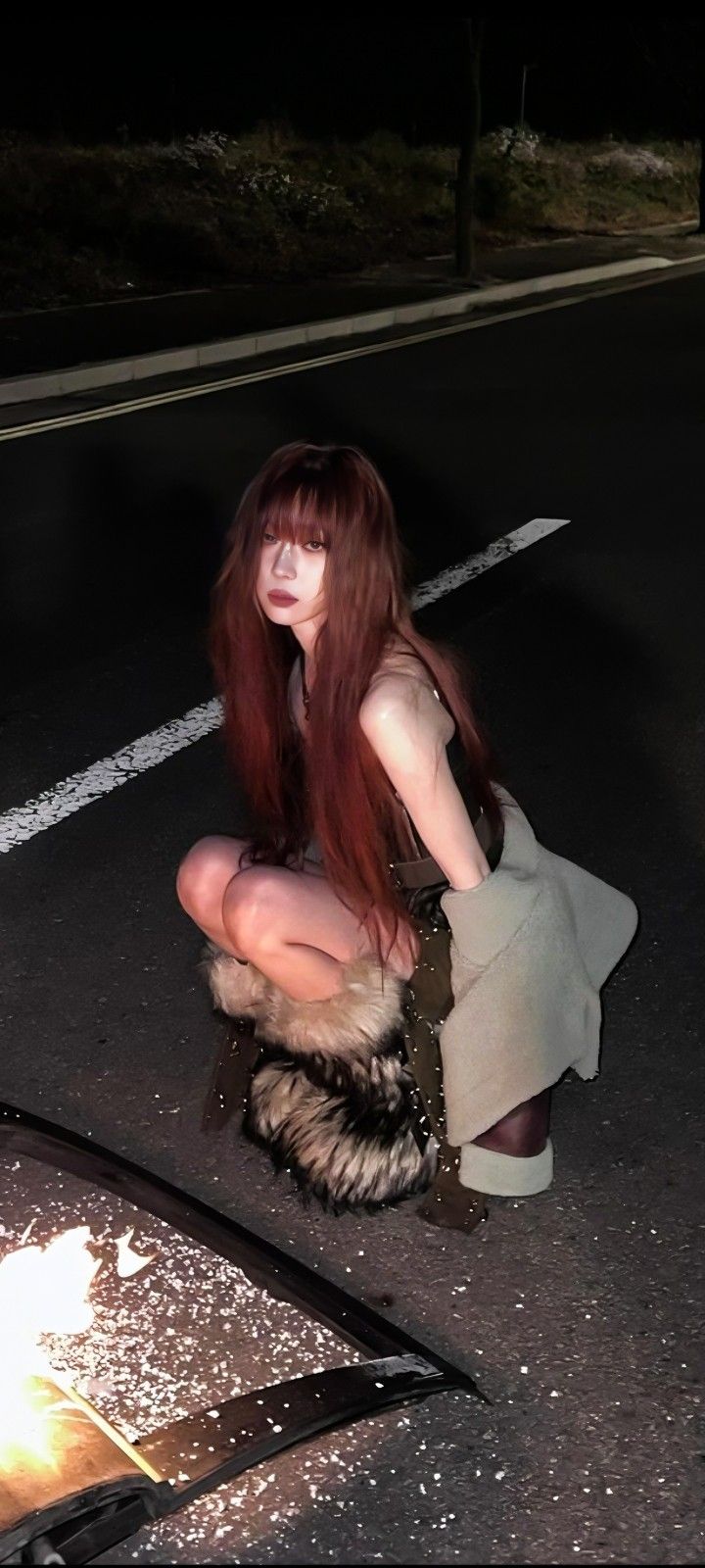 a woman with long red hair sitting on the ground