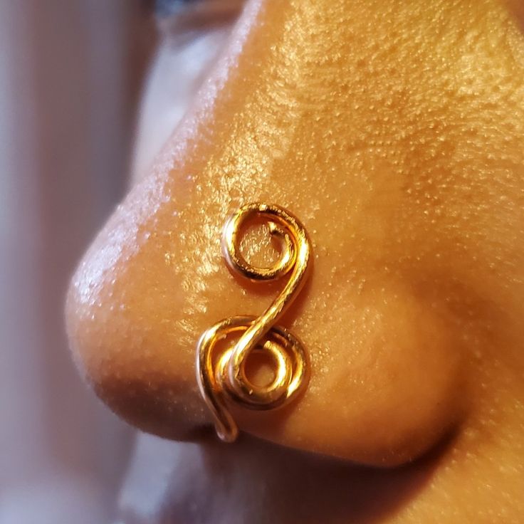 a close up view of a gold ring on the side of a person's nose