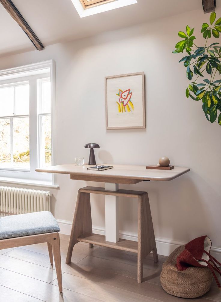 a room with a desk, chair and potted plant