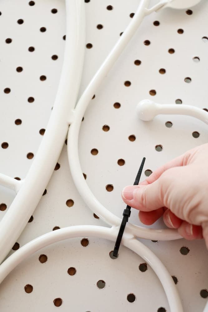 a hand is plugging wires into an electrical outlet on a white surface with holes in it