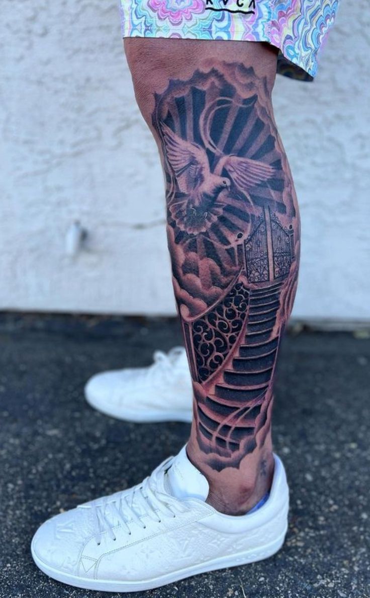 a man's leg with a bird and stairs tattoo on his left calf area