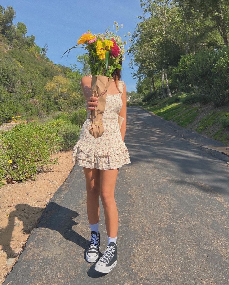 a woman walking down the road with flowers on her head and a teddy bear in her hand