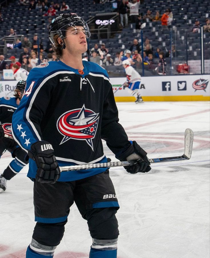 a hockey player standing on the ice in front of an audience