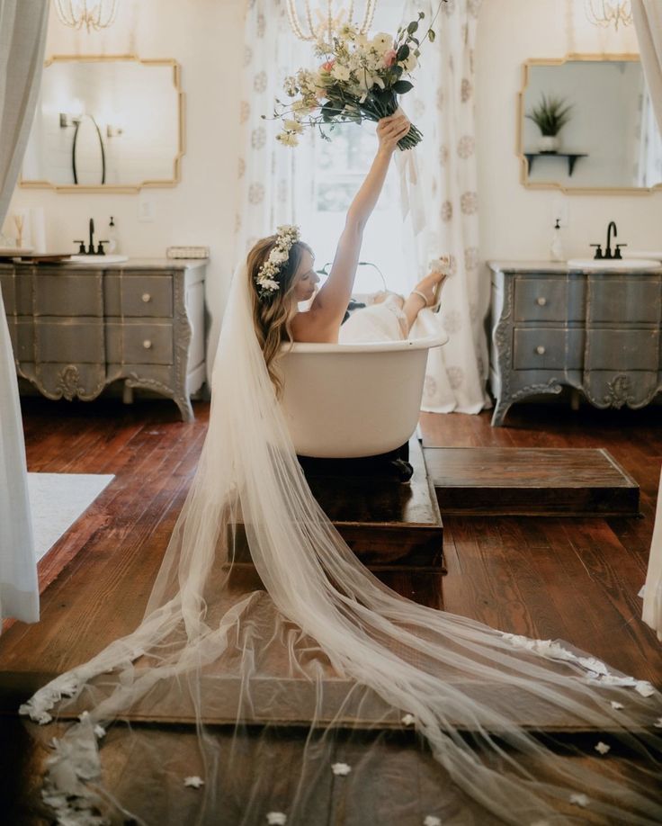 the bride is taking a bath in the bathroom with her veil flowing over her head