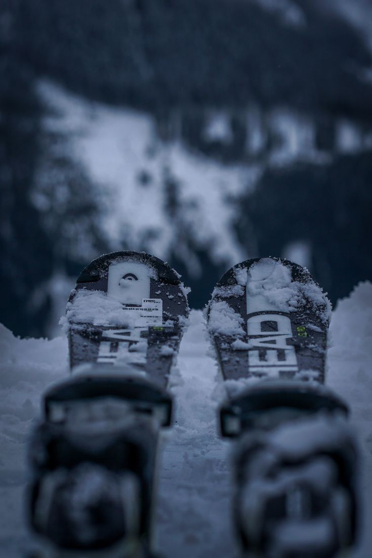 two snowboarders are standing in the snow with their feet propped up on them