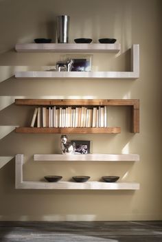 three shelves with books and bowls on them in a room that has light coming through the window