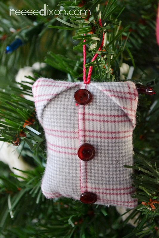 a christmas ornament hanging from a tree with red and white buttons on it