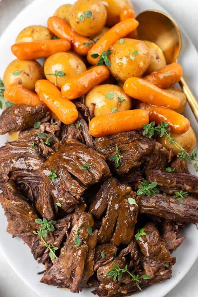 a white plate topped with meat and carrots