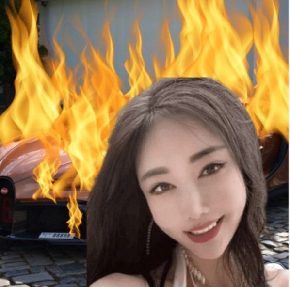 a woman with long hair standing in front of a car on fire and smiling at the camera