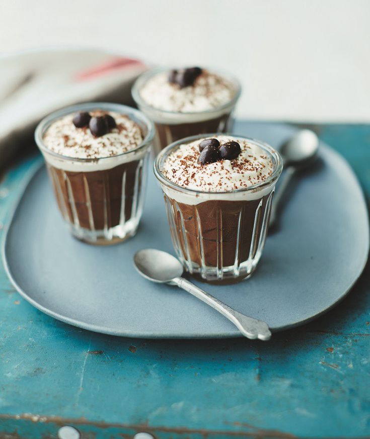 three desserts with chocolate and whipped cream on a blue plate next to a spoon