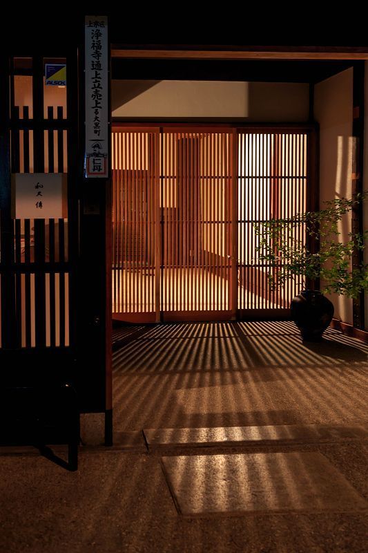 the sun is shining down on an open room with wooden doors and plants in pots