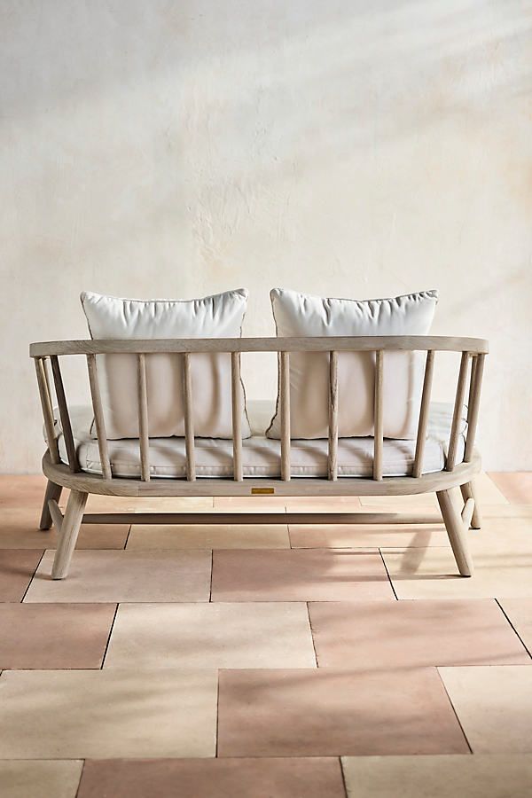 two white pillows sitting on top of a wooden bench in front of a beige wall