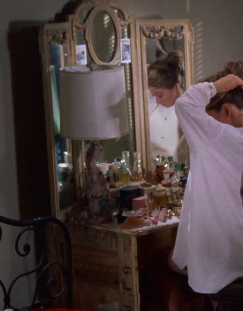 a woman standing in front of a dresser with a mirror on it's side