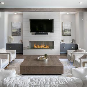 a living room with white furniture and a flat screen tv mounted above the fire place