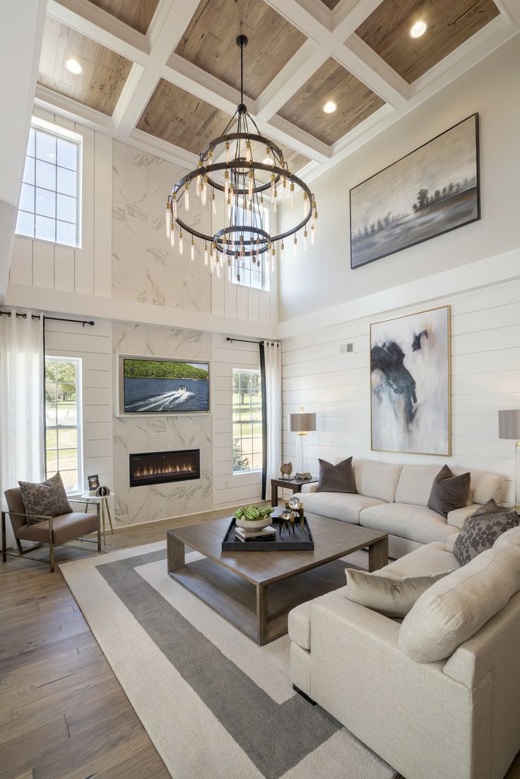 a living room filled with furniture and a chandelier hanging from the ceiling over a fire place