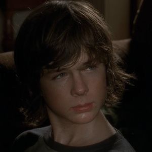 a young boy sitting in a chair looking at the camera with an intense look on his face