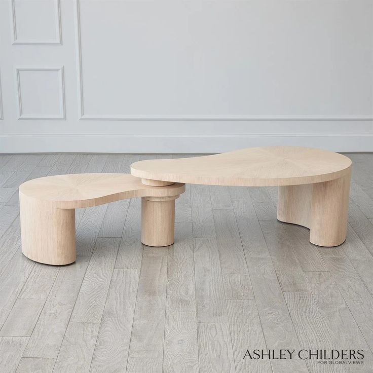 two wooden benches sitting on top of a hard wood floor next to each other in front of a white wall