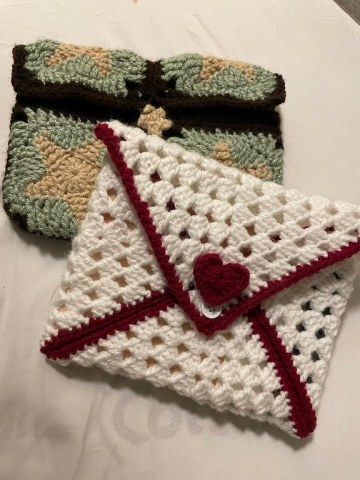 two crocheted purses sitting on top of a white table next to each other