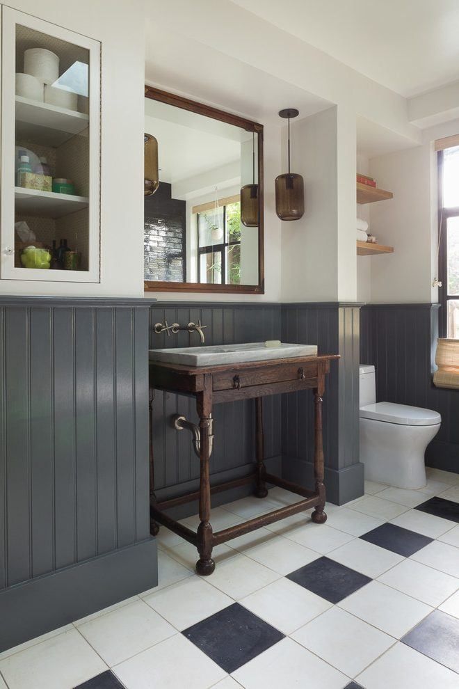 a bathroom with black and white tile flooring and gray walls, along with a wooden vanity