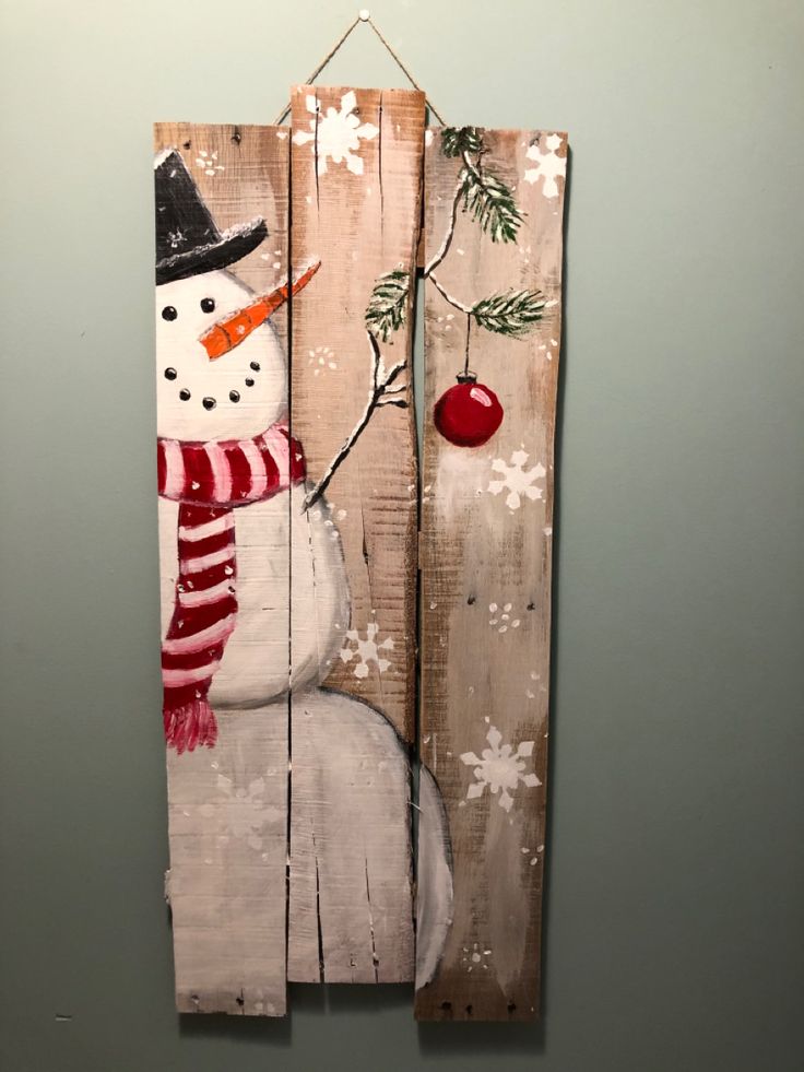 a wooden sign with a snowman and an apple hanging from it's side