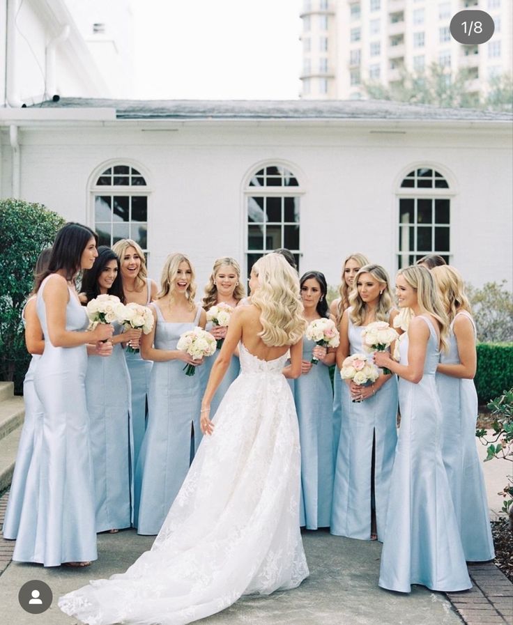 a bride and her bridal party in front of a white building