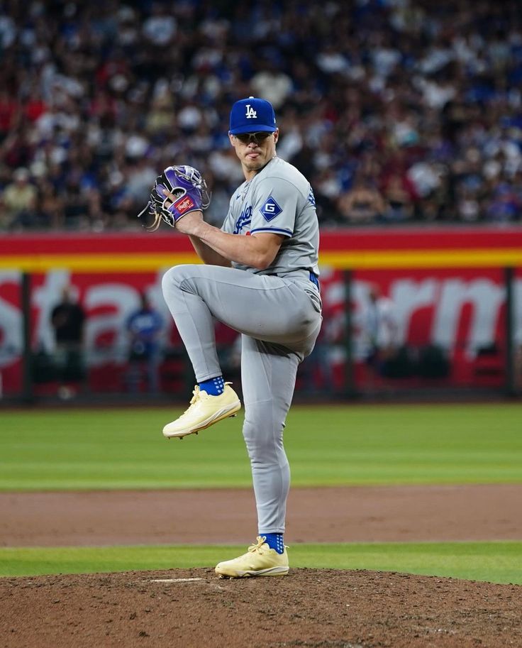 a baseball player pitching a ball on top of a field in front of a crowd