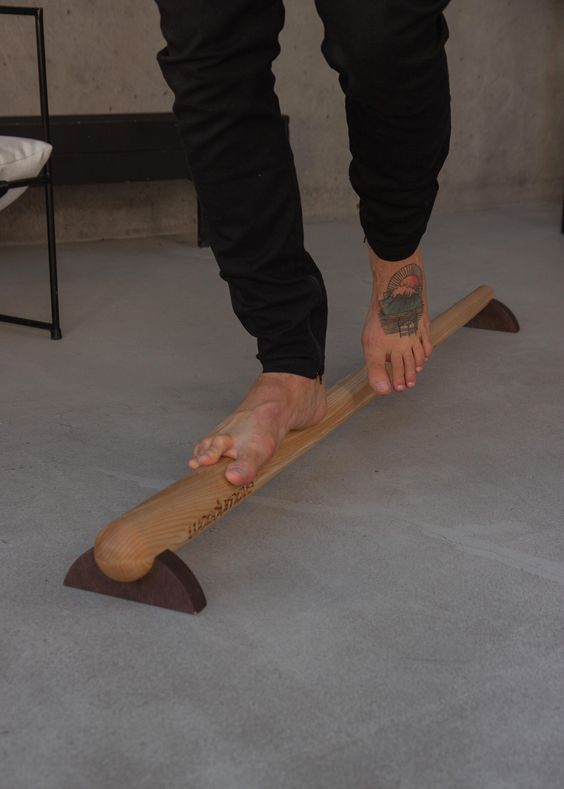 a man standing on top of a wooden stick with his foot sticking out of it