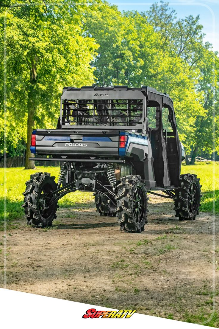 a large truck parked on top of a dirt road next to trees and grass in the background