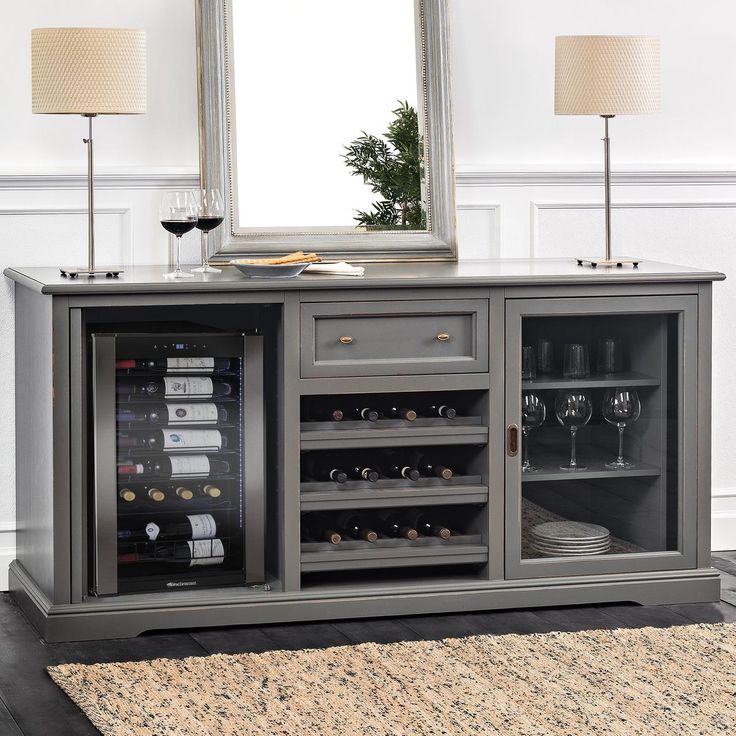 a wine cabinet with many bottles and glasses on it in front of a large mirror