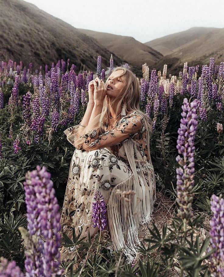 a woman sitting in the middle of a field of purple flowers