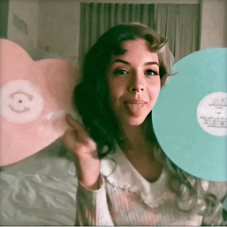 a woman holding up two discs in front of her face and smiling at the camera