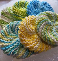 four different colored knitted scrubcloths sitting on top of a white countertop