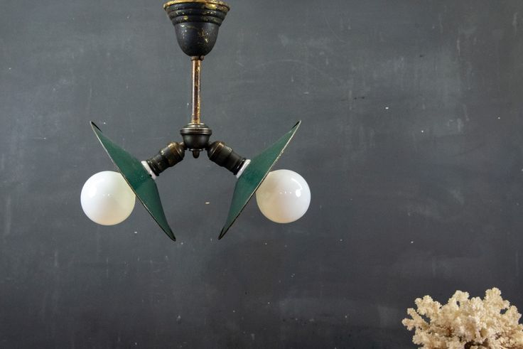 two green and white lights hanging from a black ceiling fixture in a room with gray walls