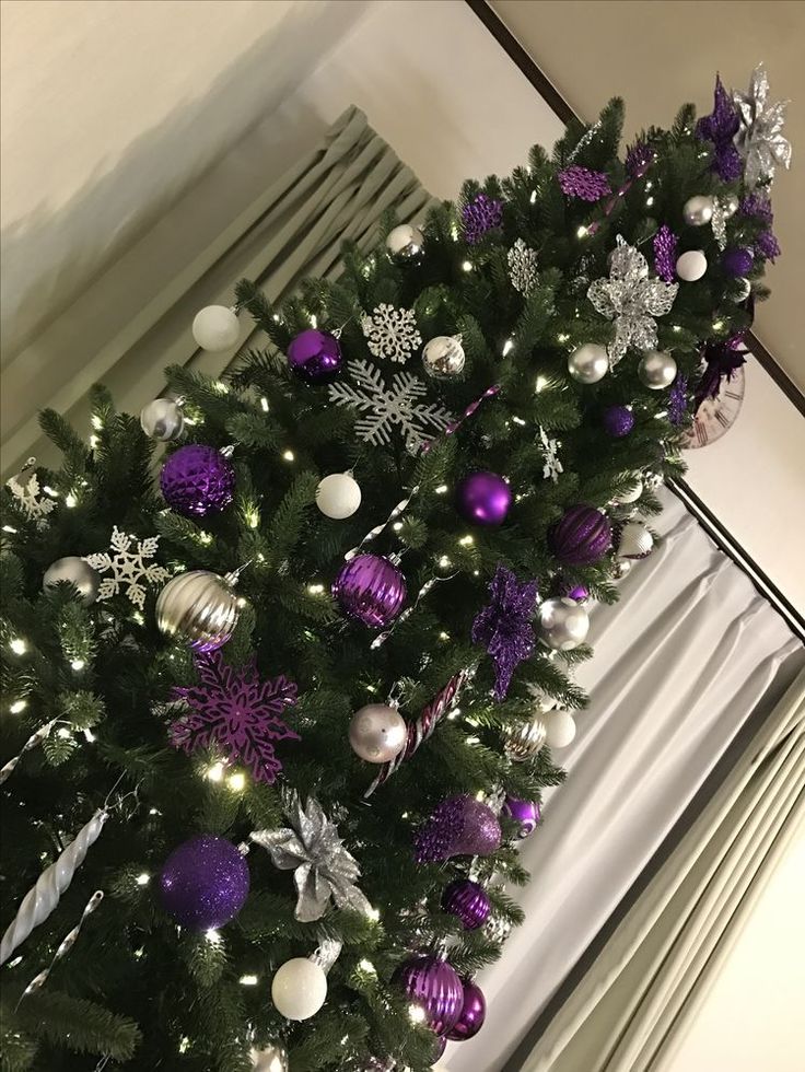 the christmas tree is decorated with purple and silver ornaments