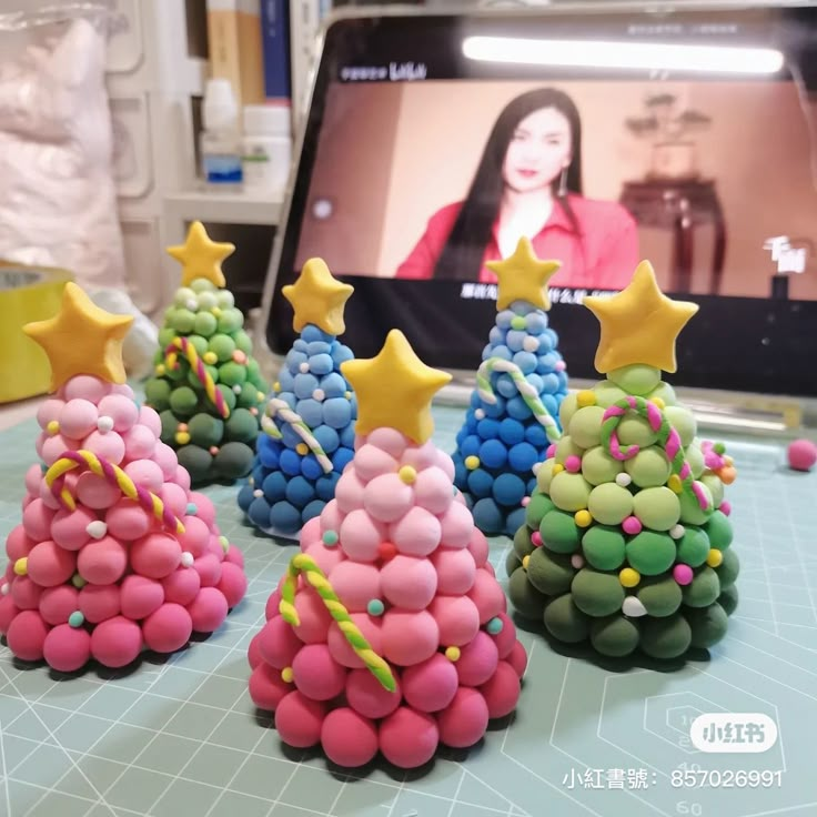 three small christmas trees made out of candy on a table with a television in the background