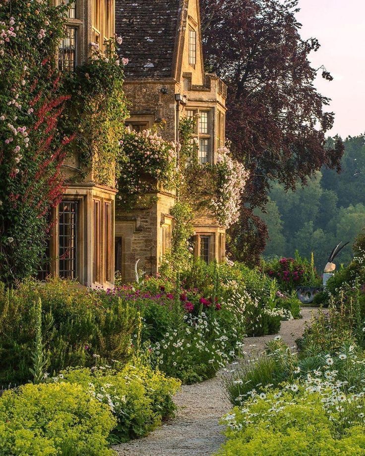 an old house surrounded by flowers and greenery