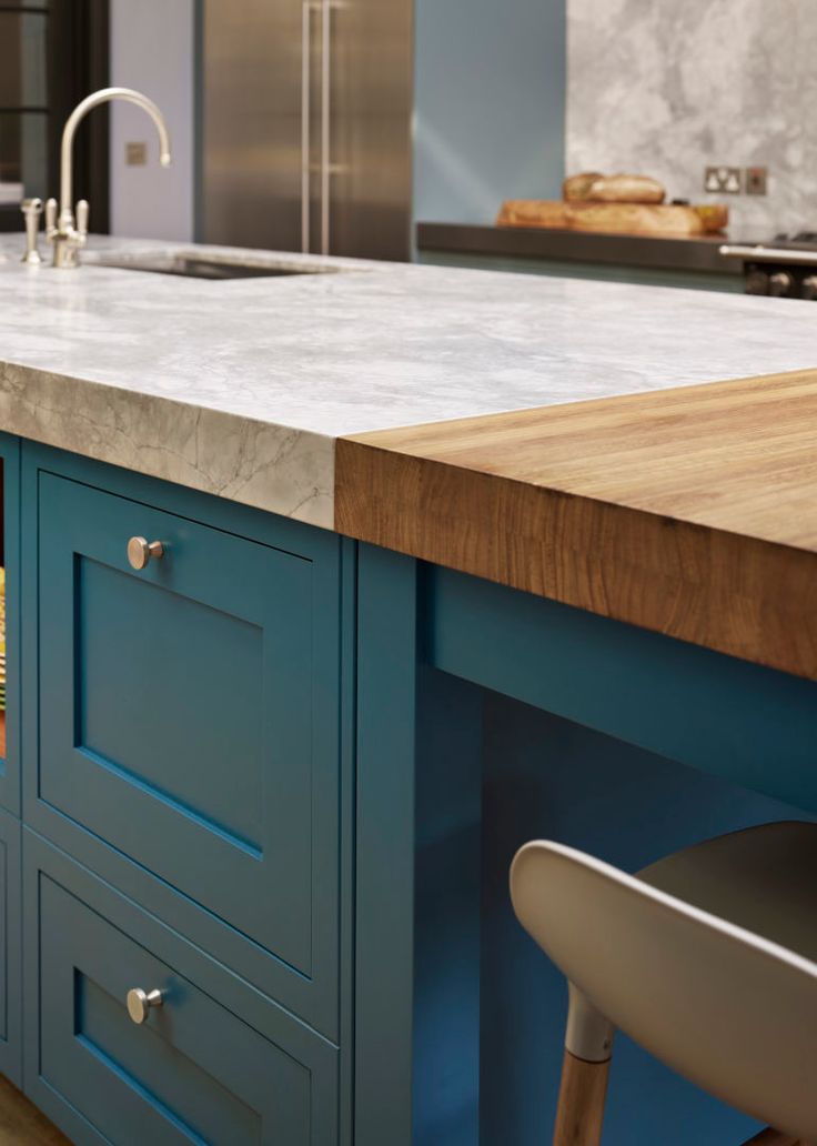 a kitchen island with blue cabinets and marble counter tops in an open concept home setting