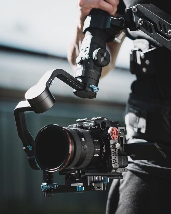 a person holding a camera with a video attached to it's body and arm